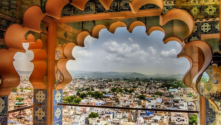 Historic city view through a traditional Rajasthani palace window in Jaipur, showcasing the scenic beauty of solo travel in India.