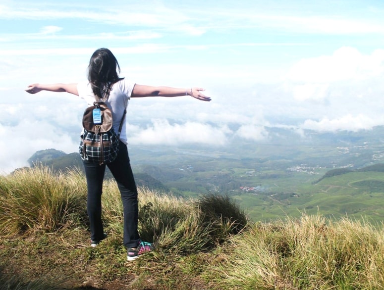 Empowered female solo traveler enjoying the scenic mountain views in India, representing safe and organized women-only travel packages. 